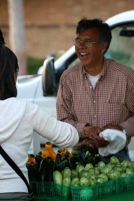 Two women at a produce stand, one holding leafy greens